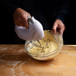 Female hands stirring dough with a mixer for cake or bread in a 