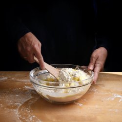 Female hands stirring dough for cake or bread in a bowl on a woo
